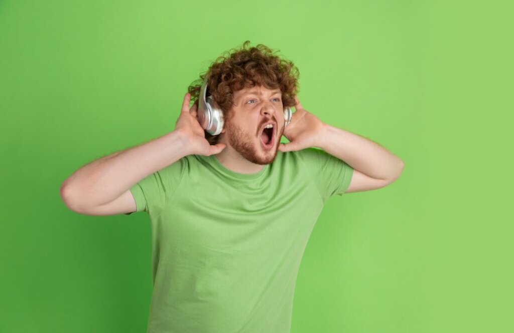 Joven escuchando música a alto volumen en auriculares, una de las principales causas de pérdida auditiva temprana